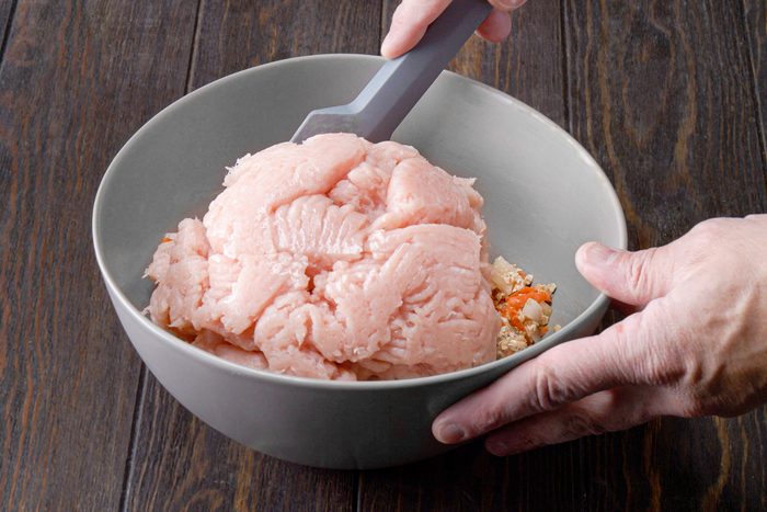 Mixing ground meat in large with other ingredients