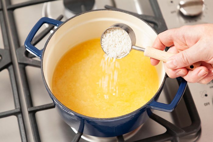 Putting uncooked rice in a pot for cooking