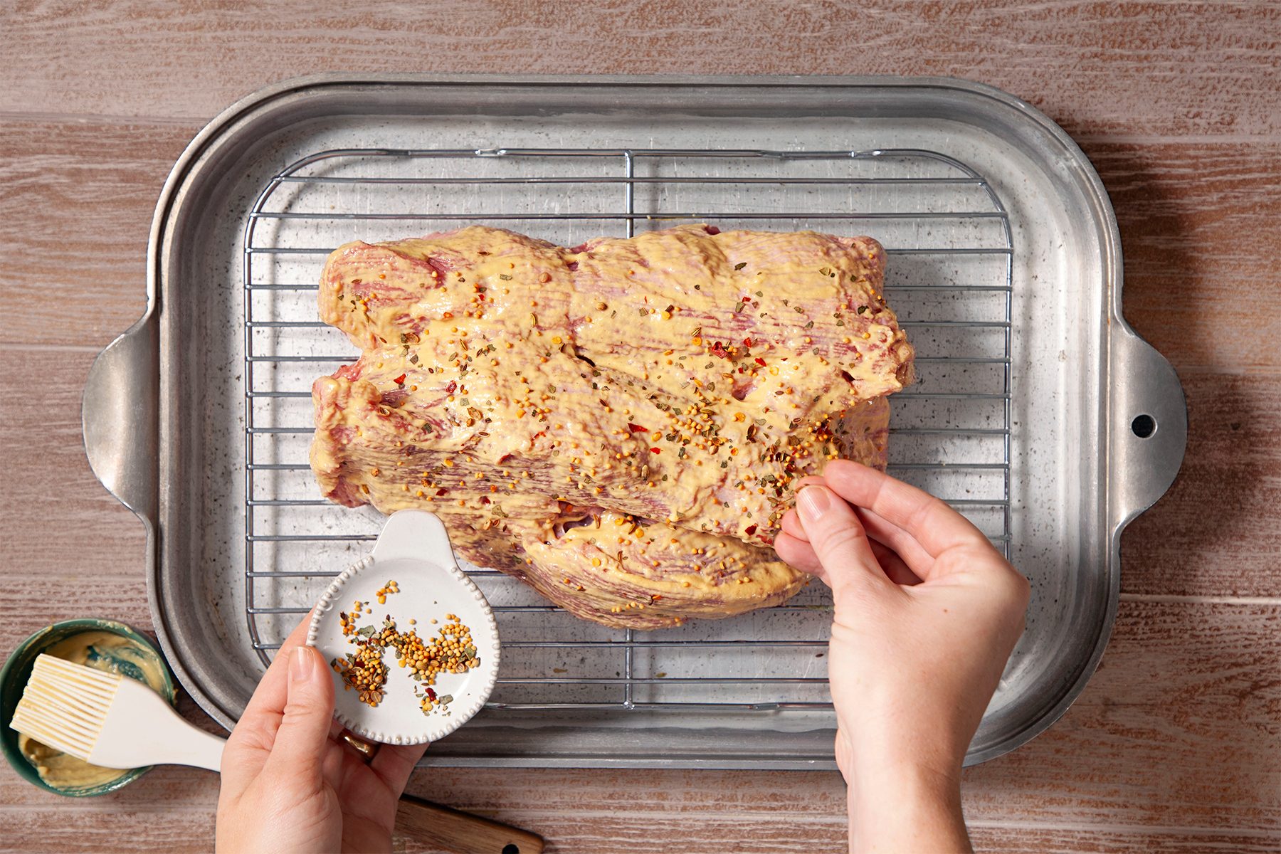 A person is sprinkling spices on the meat