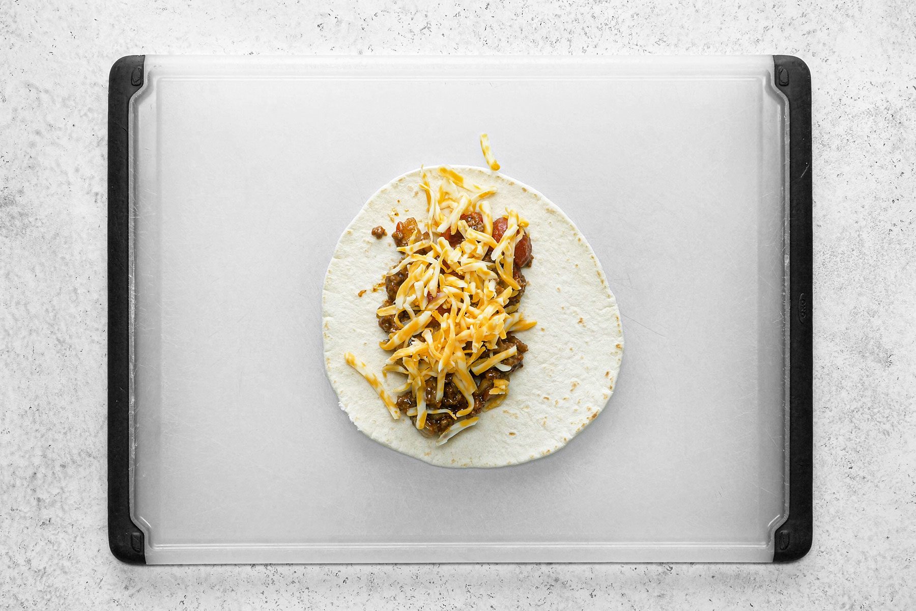 Cheese and sauce on tortillas on table top