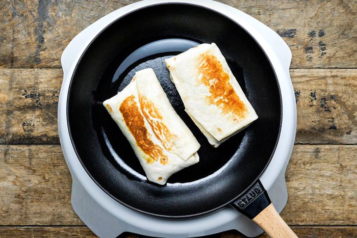 cooking Burritos in a pan on an induction cooktop on wooden surface