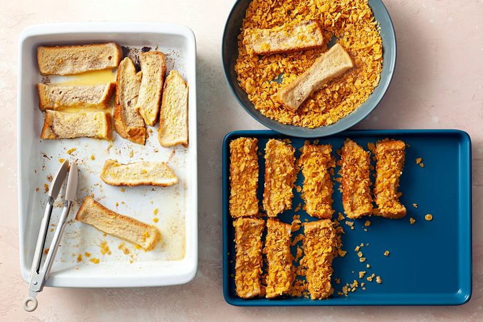 Coating soaked bread sticks in cornflakes