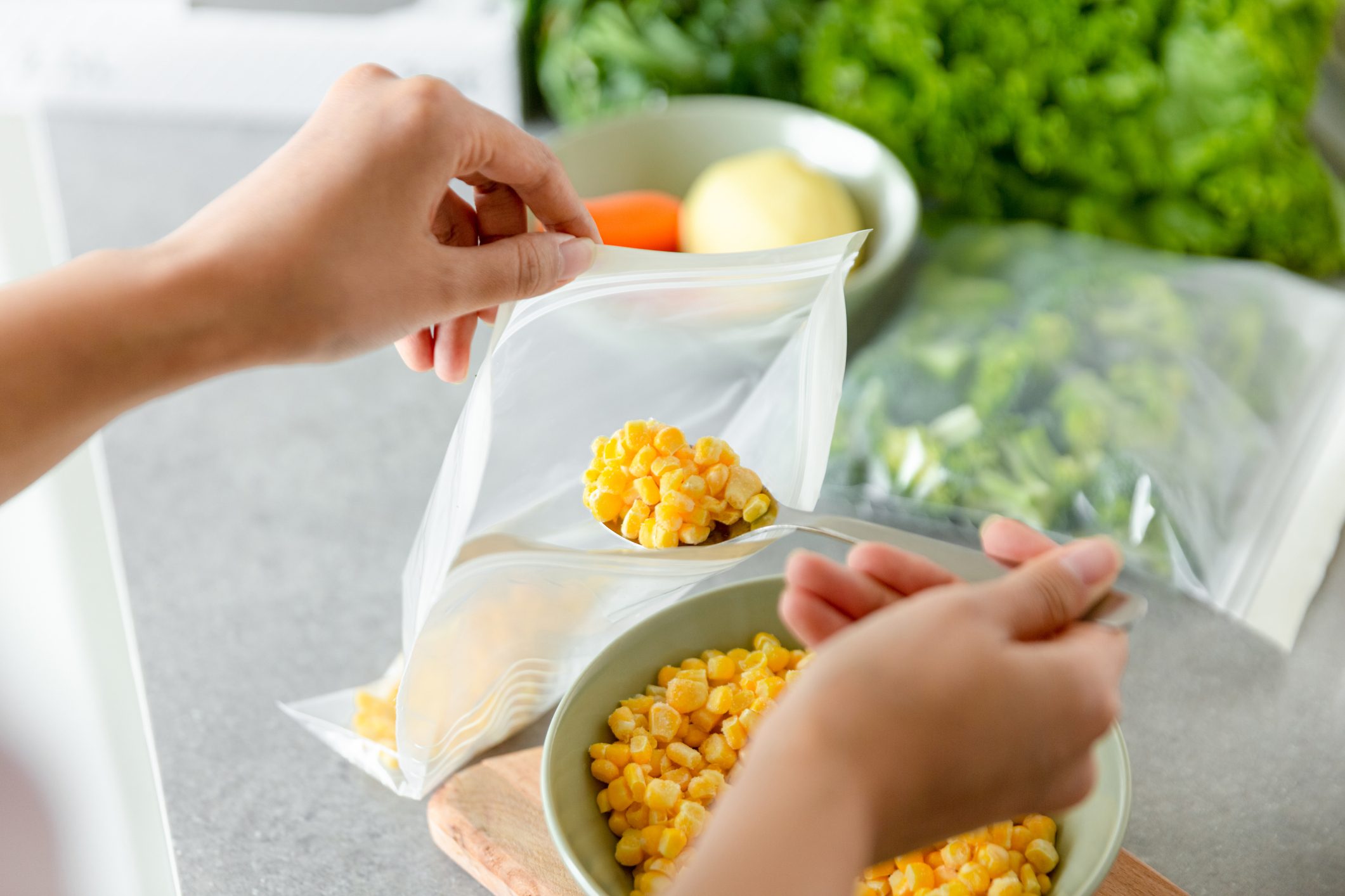 Woman preparing corn for freezing on kitchen