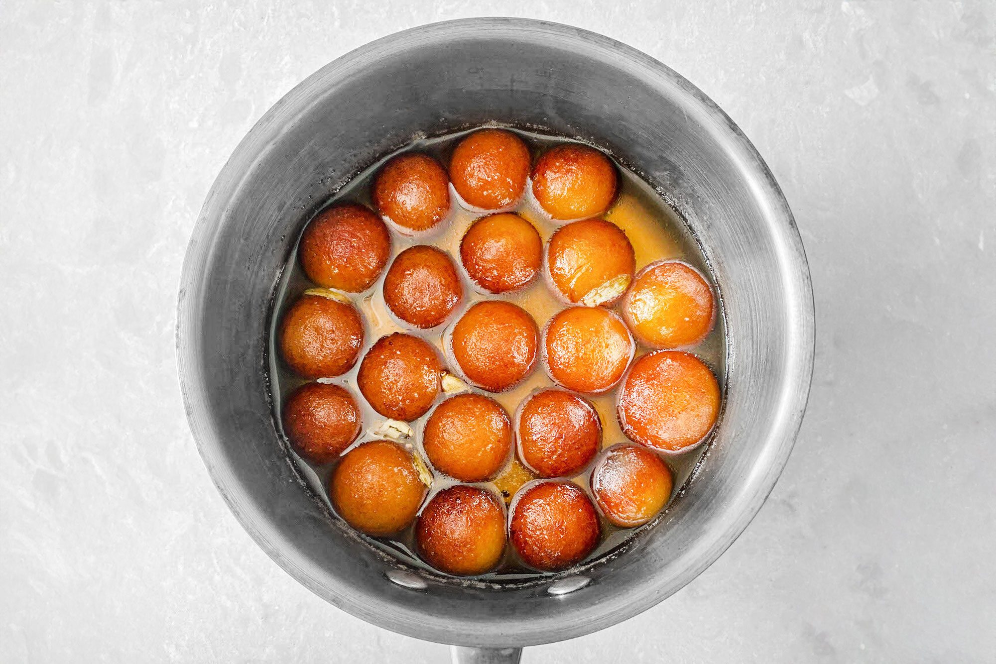 a lot of Gulab Jamun in a saucepan of sugar syrup