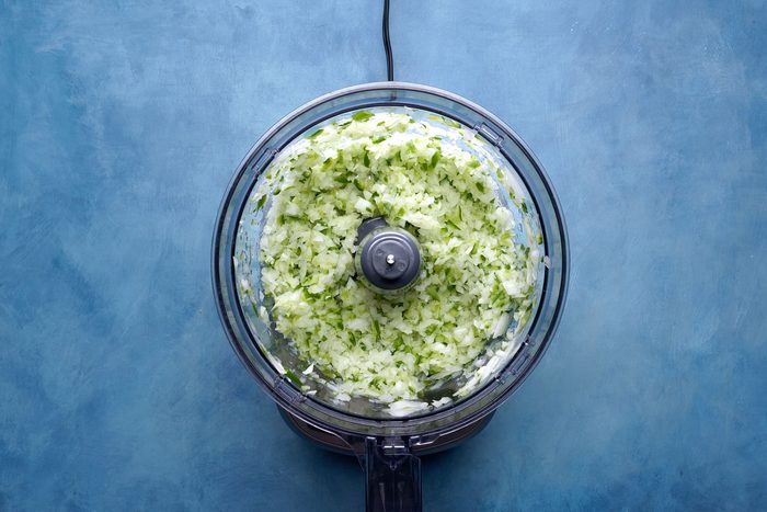 Onion and peppers in a food processor on a countertop