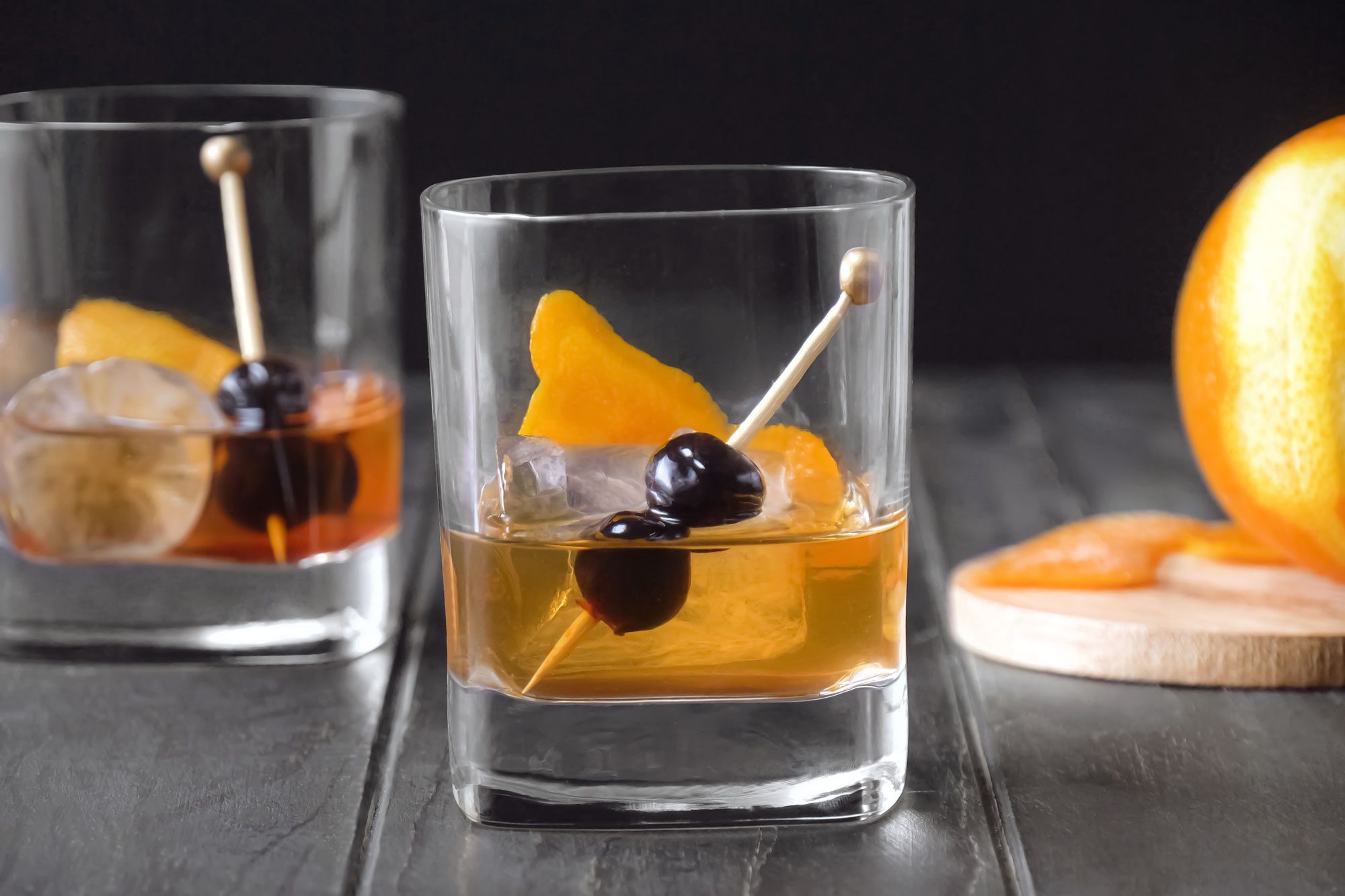 Old-Fashioned served in glasses and garnished with orange peel and cherries