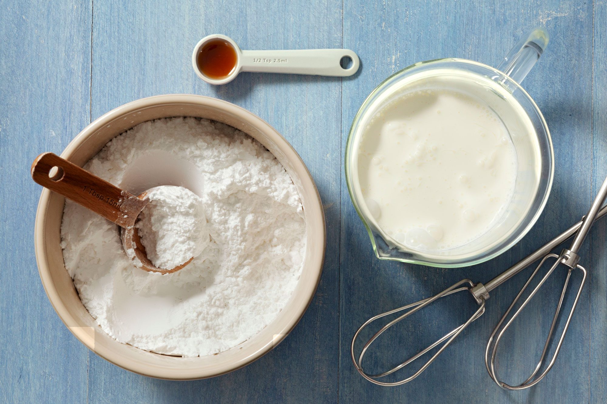 All Ingredients and Equipment for Sweetened Whipped Cream on a Textured Light Blue Surface