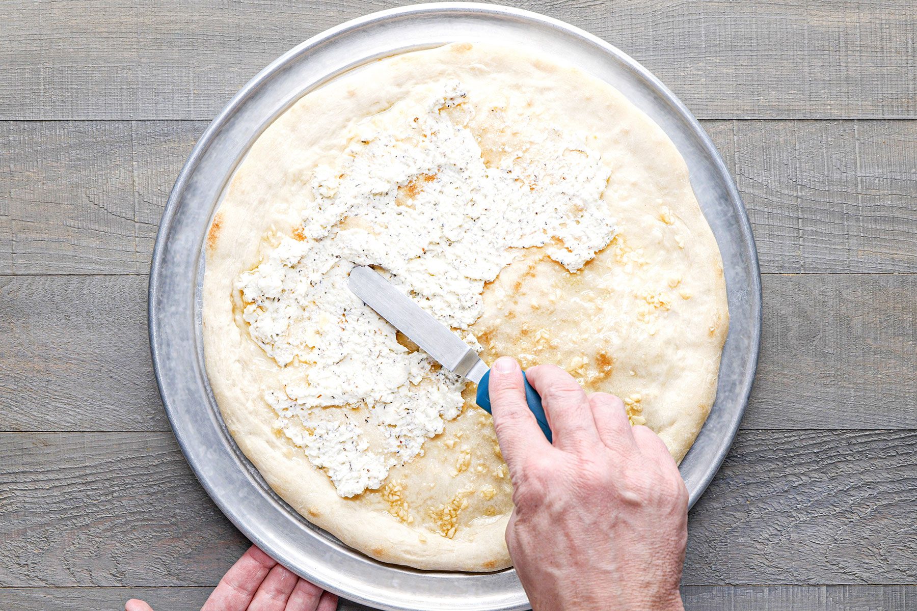 Spreading ricotta mixture over pizza base