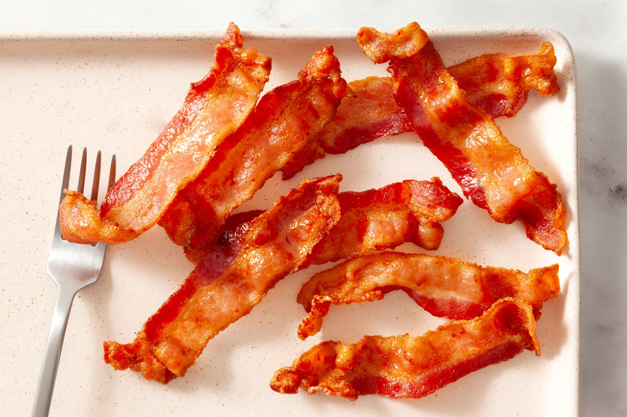 Air Fryer Bacon in a serving dish with a fork