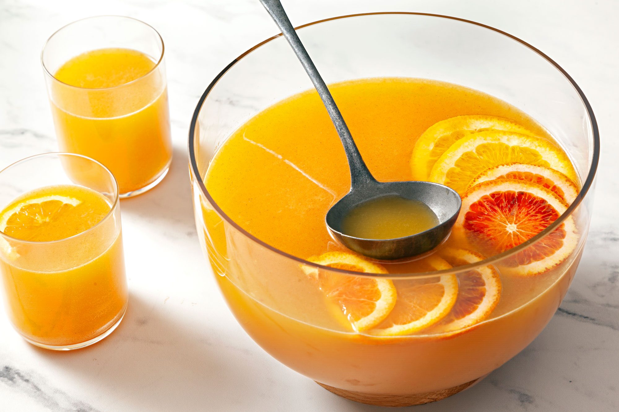 Two glasses and bowl of Apple Cider Punch garnished with orange slices