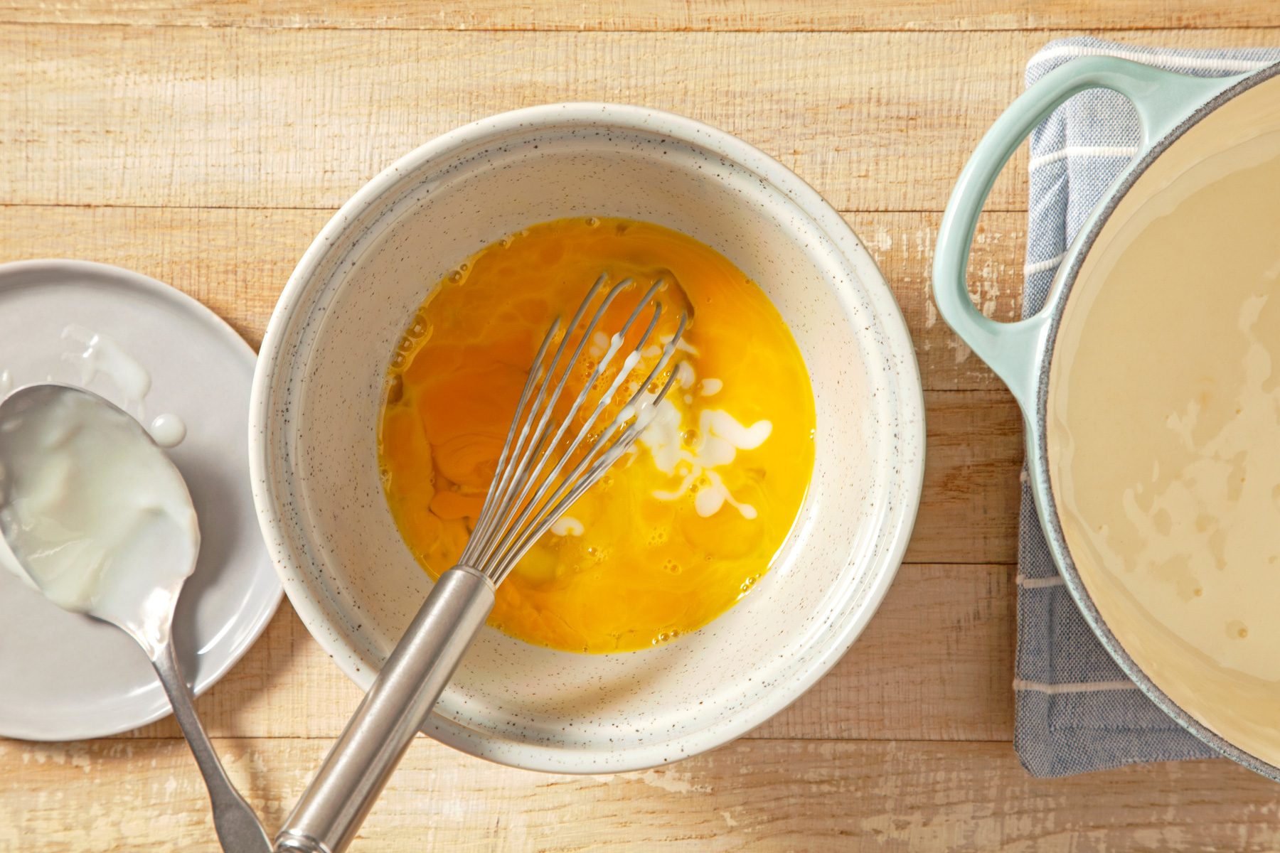 A bowl of egg mixture with a whisk