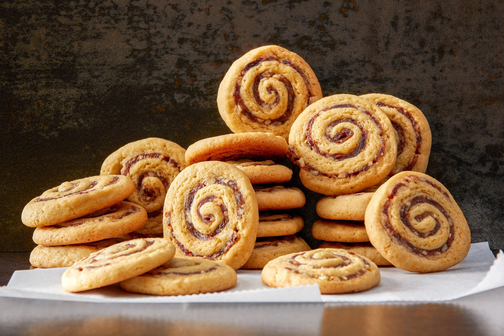 Table View Shot of Date Pinwheel Cookies; baking paper; dark background;