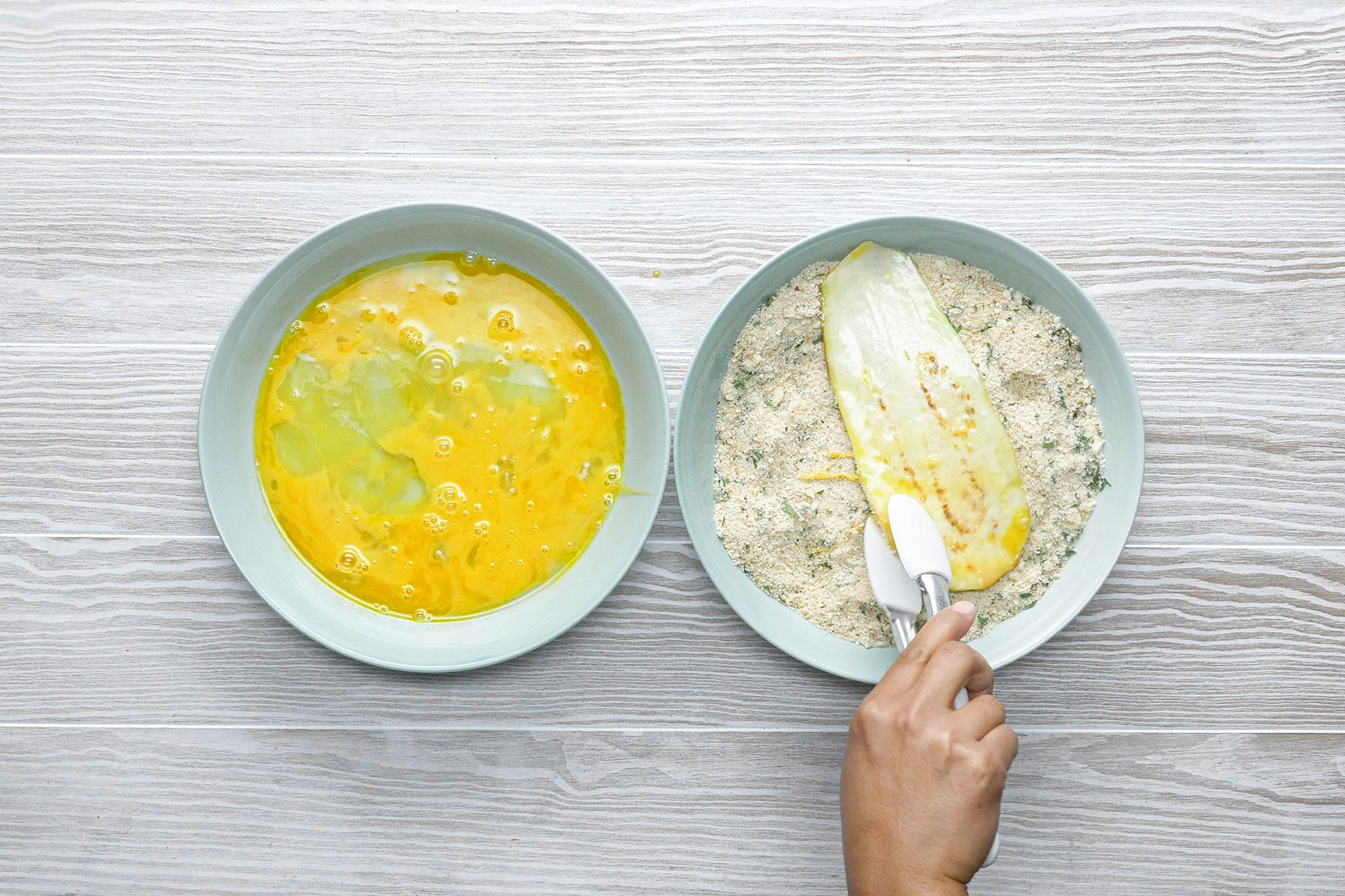 Dipping eggplant slice in bread crumbs 