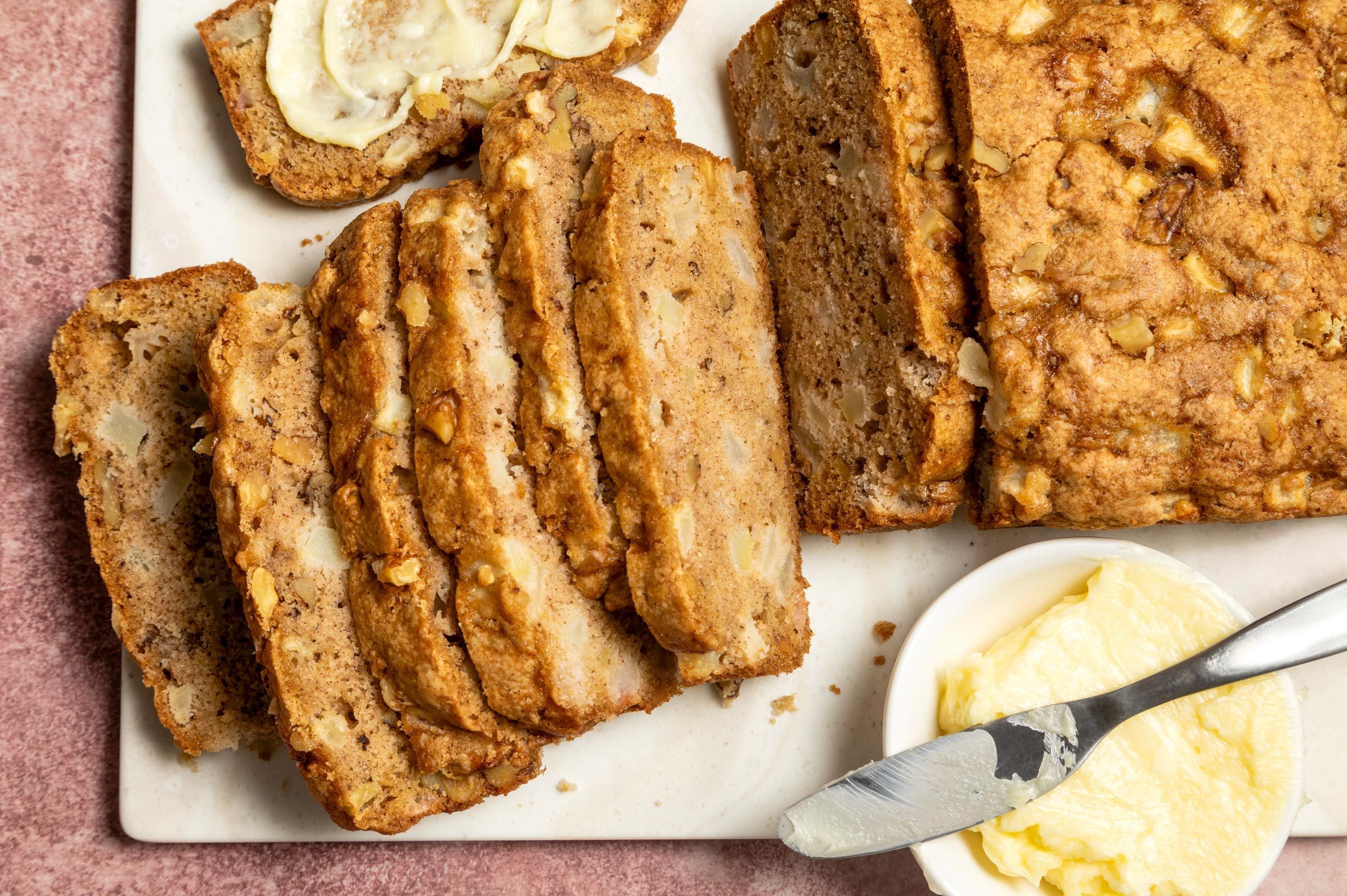 fresh Pear Bread on a cutting board cut into slices with a side of butter