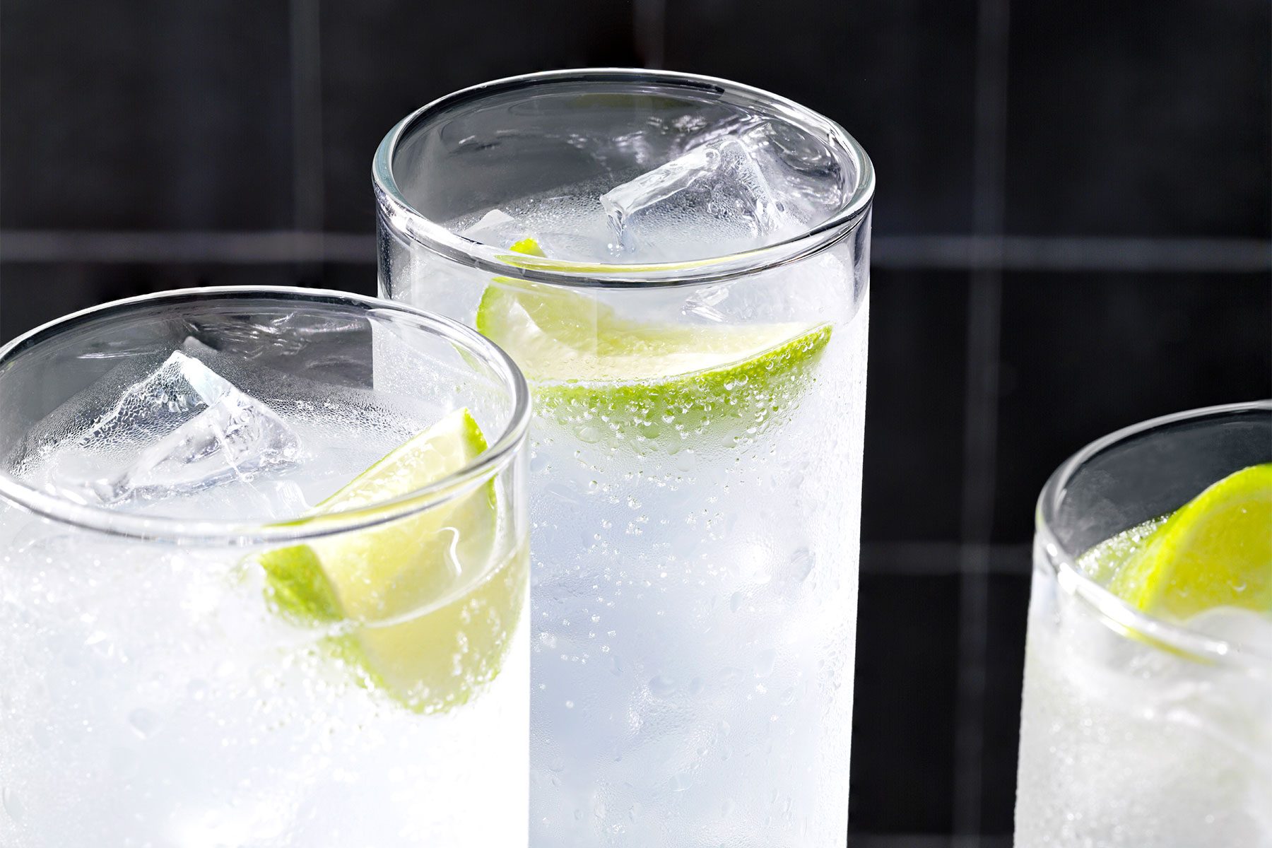 Close shot of Gin Rickey; served in three collins glasses; garnished with lime wedge;