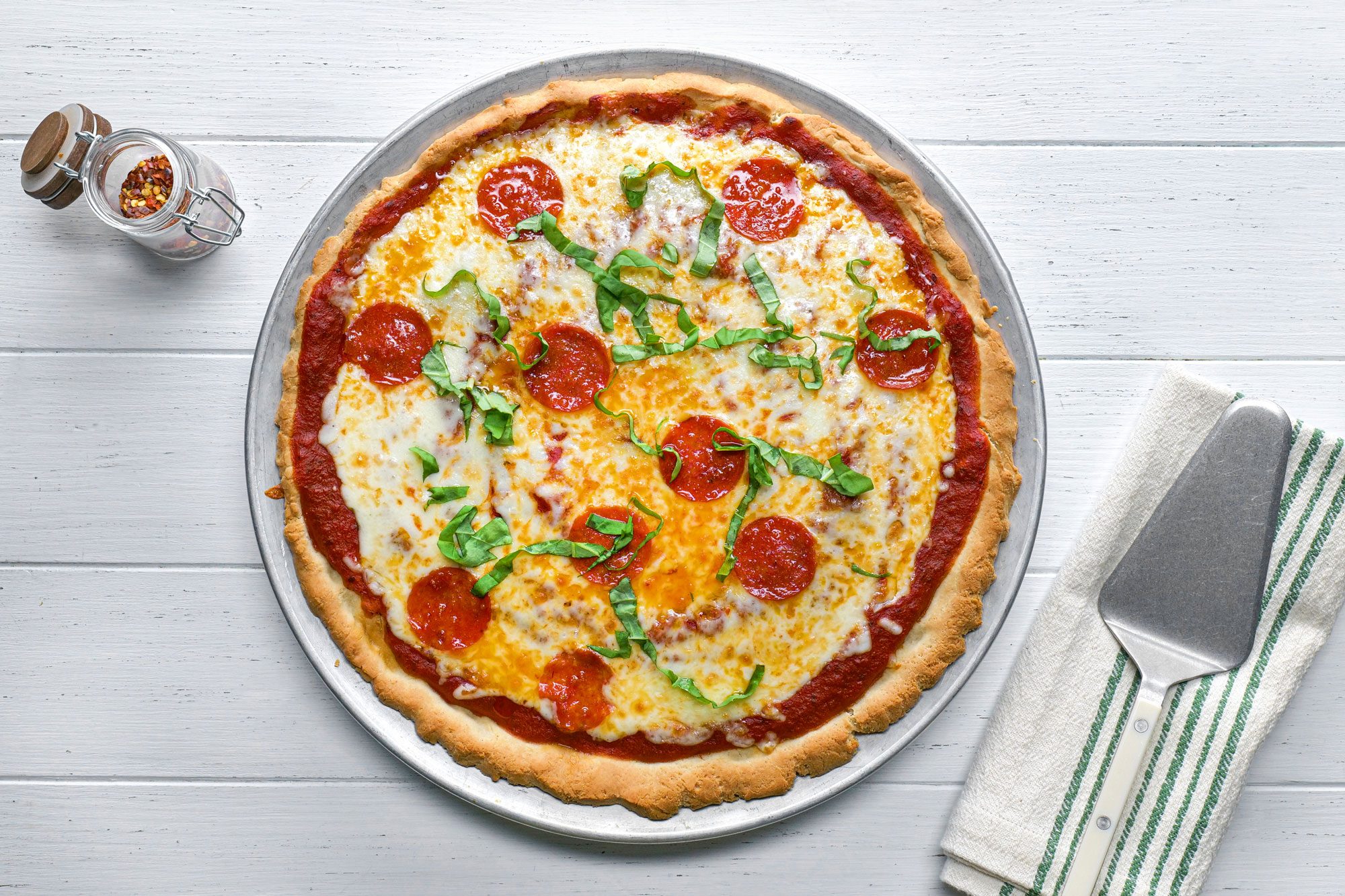 Gluten Free Pizza on a plate on white painted wooden surface
