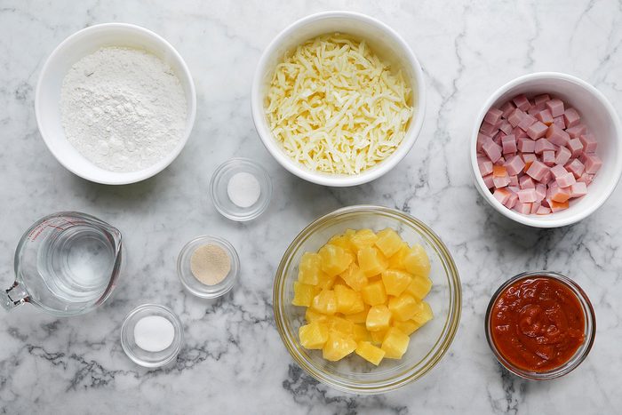 Homemade pizza dough Pizza sauce Ham and other ingredients on a countertop