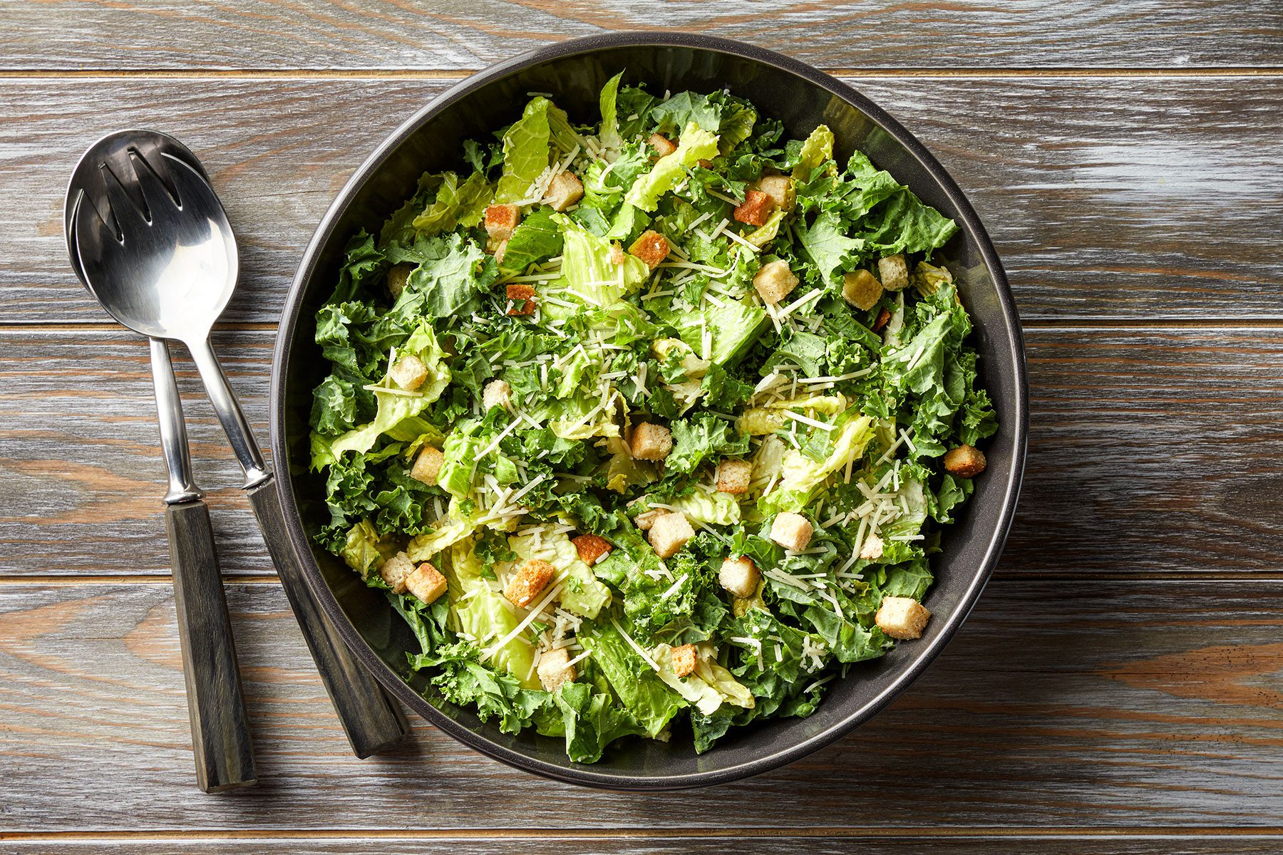 A bowl of salad with croutons and cheese