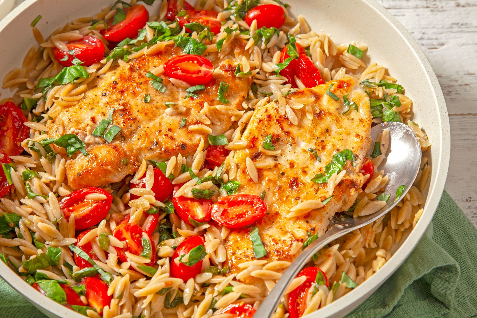A bowl of Lemon Chicken with Orzo, topped with succulent chicken and juicy tomatoes