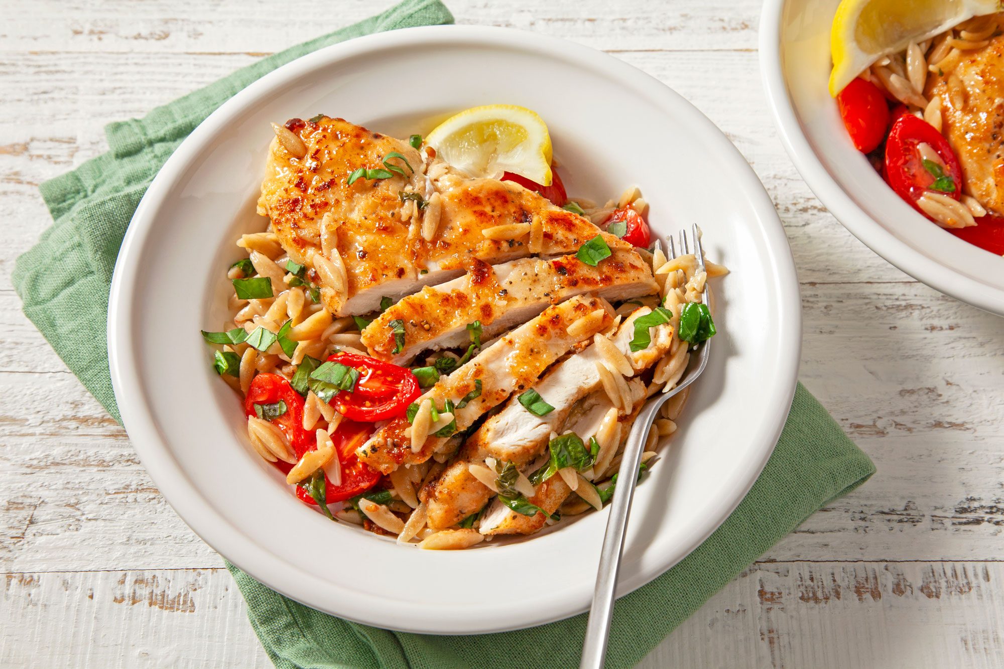 A delicious bowl of Lemon Chicken with Orzo, topped with tender chicken and tomatoes
