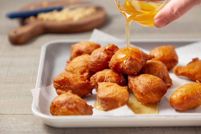 Drizzle honey syrup over the doughnut balls in a serving pan