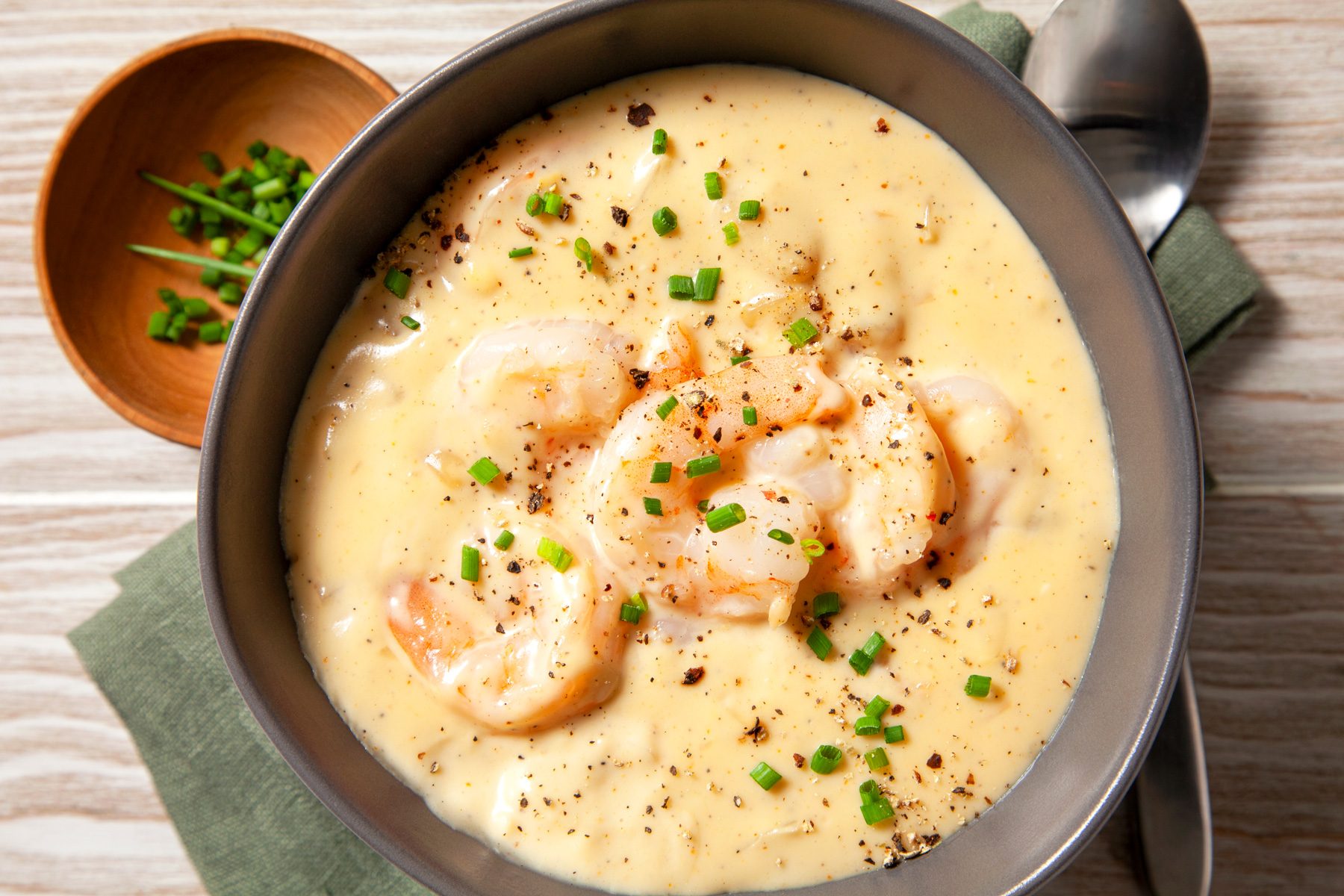 Shrimp Chowder served in large bowls placed over kitchen towel with one silver spoon 