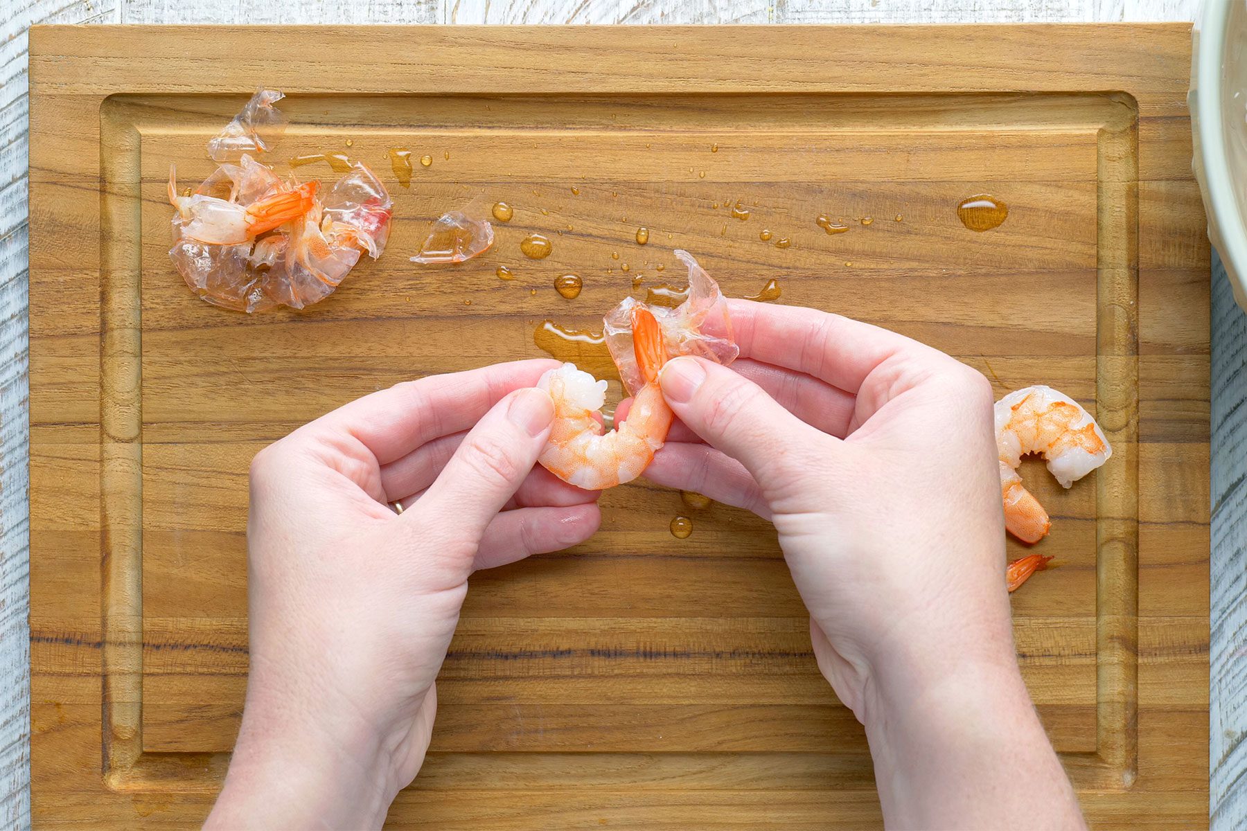 overhead shot of peeling shrimps on a wooden plank