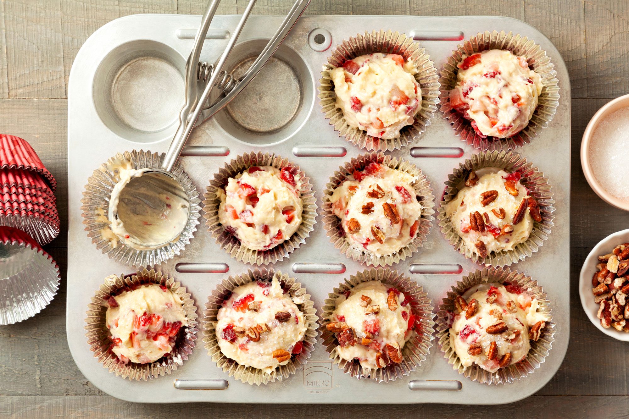 Filling Strawberry Muffin Batter in a Muffin Tray on a Wooden Surface