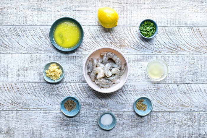overhead shot; white wooden background; all ingredients for baked shrimps;