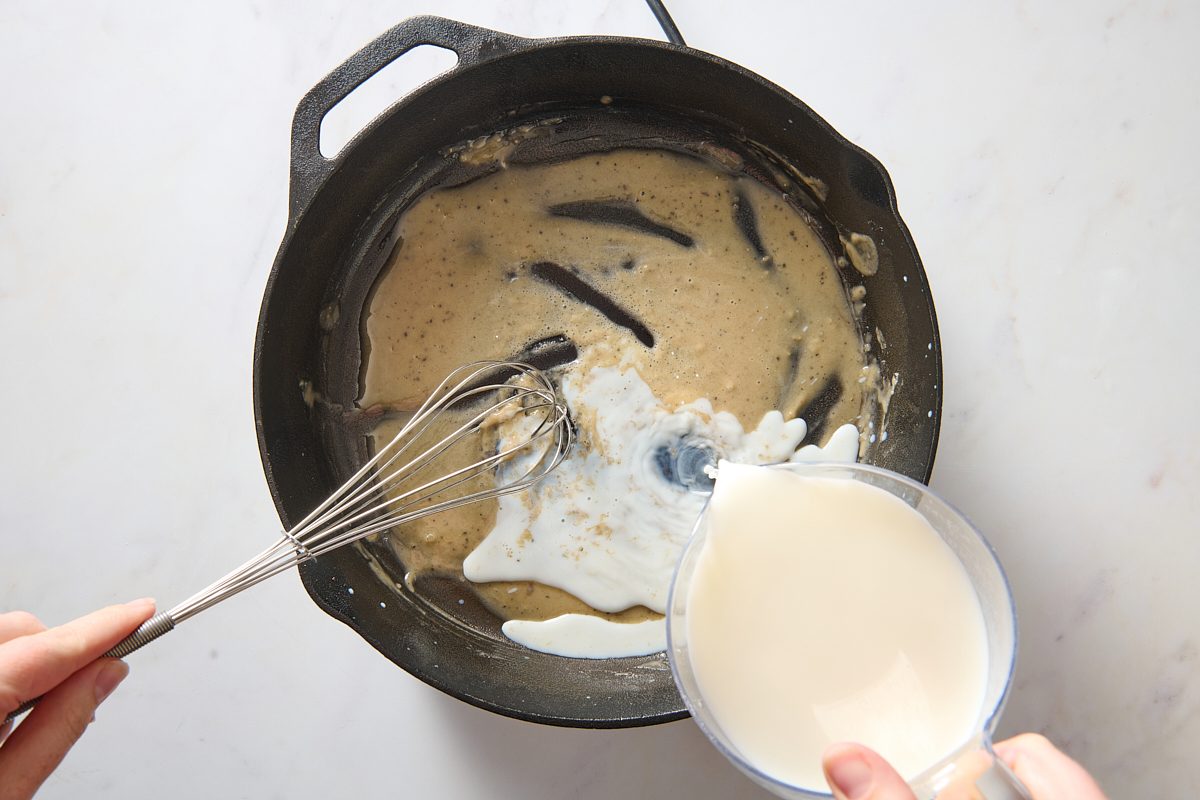 Whisking milk into the flour and meat juices in a cast iron skillet