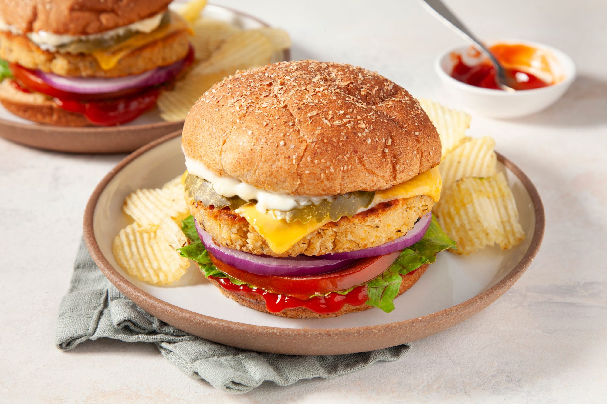 3/4th shot; white background; Chickpea Burger served over a plate with chips;