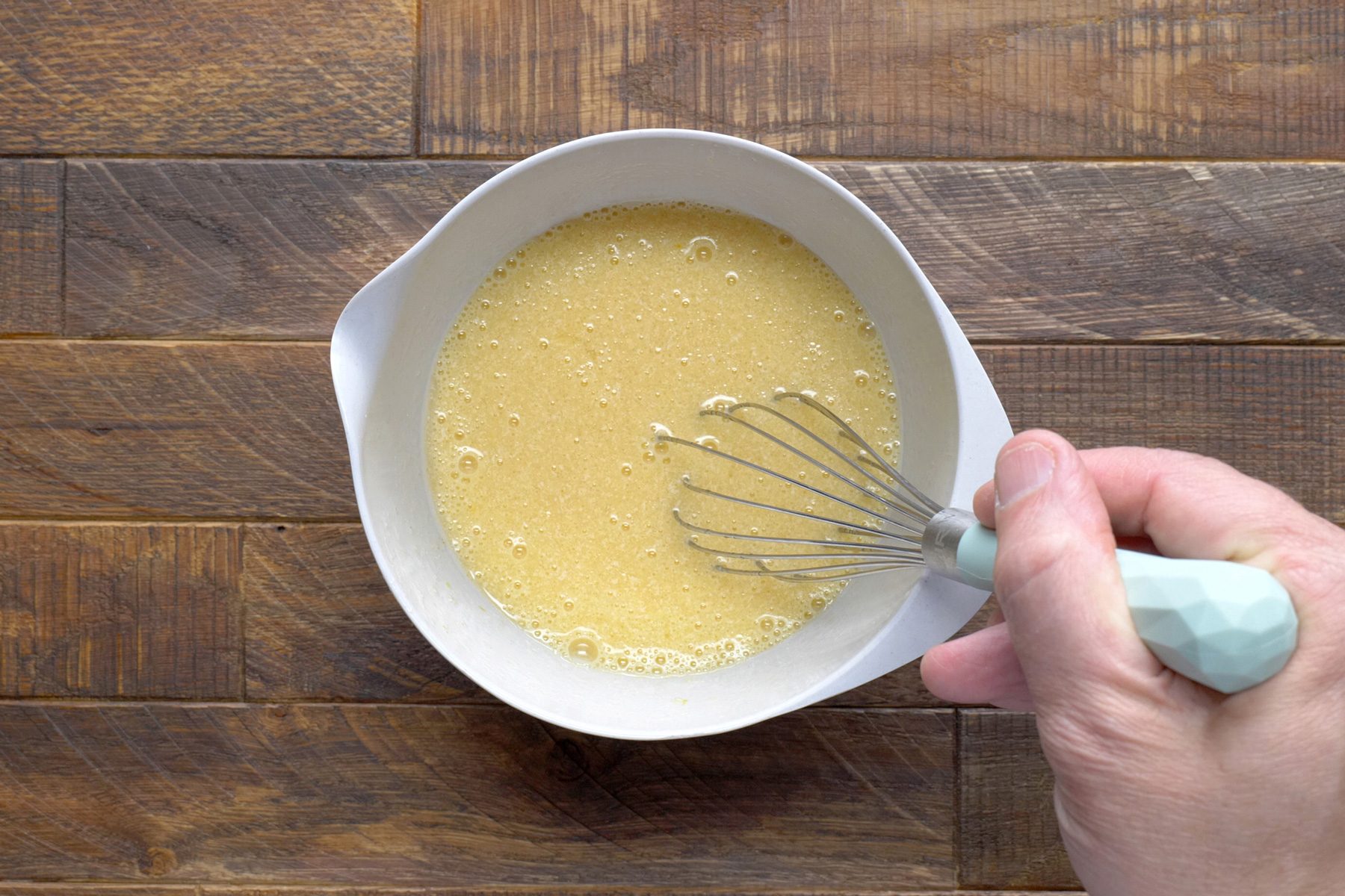 A hand whisking an egg mixture