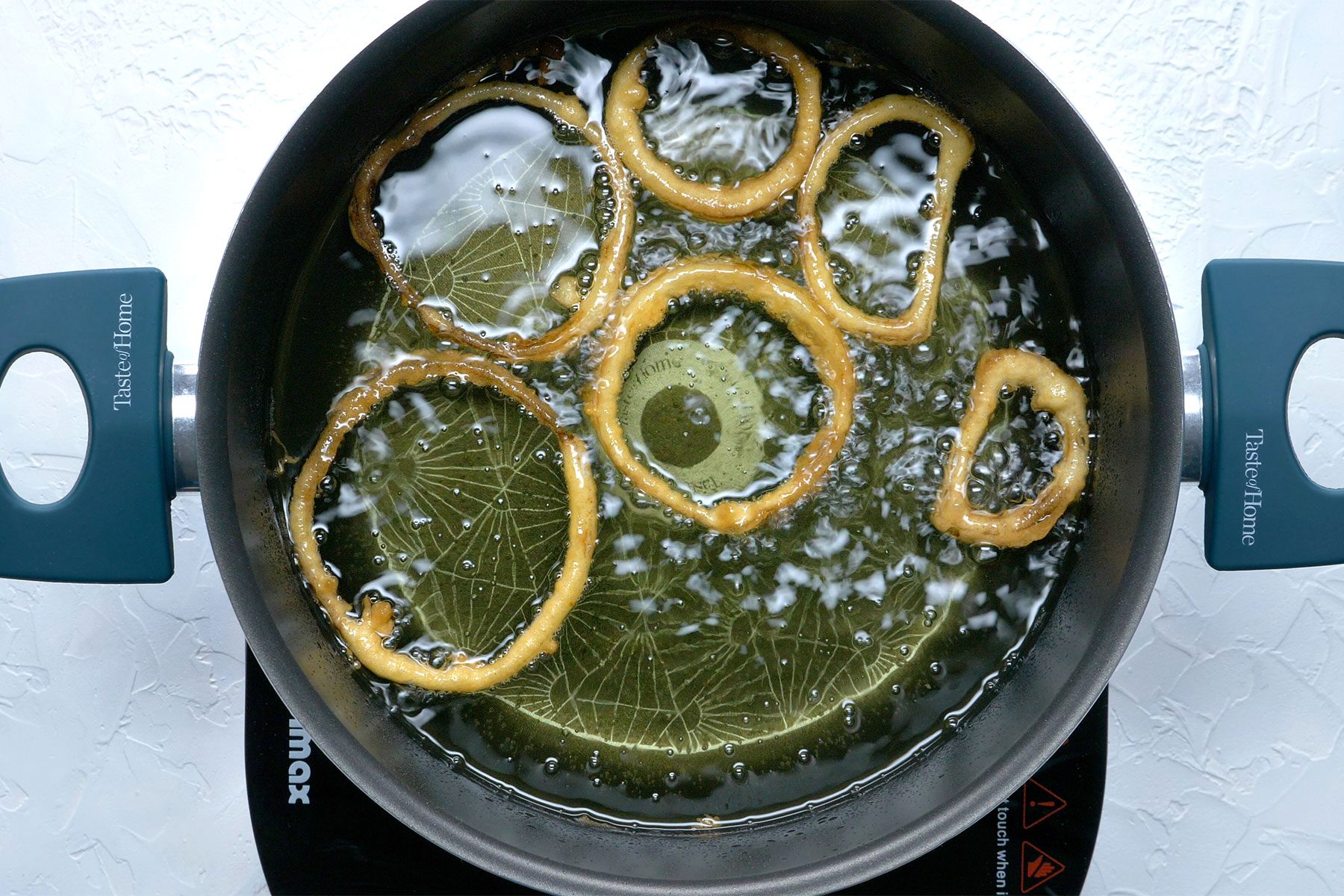 overhead shot; white textured background; In a deep-fat fryer, In batches, fry onion rings until golden brown;