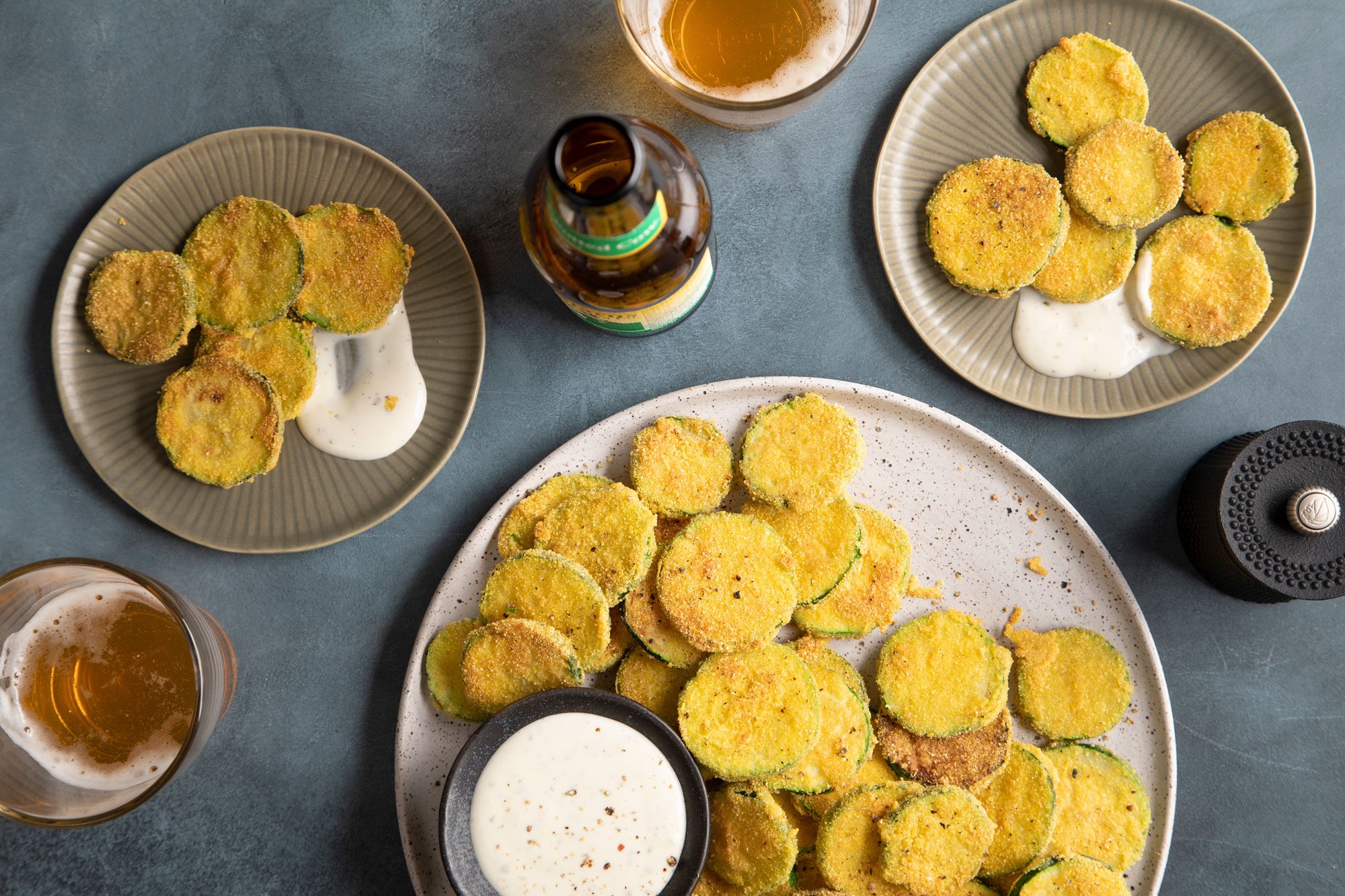 Overhead shot of Fried Zucchini served on round plates on a dark background