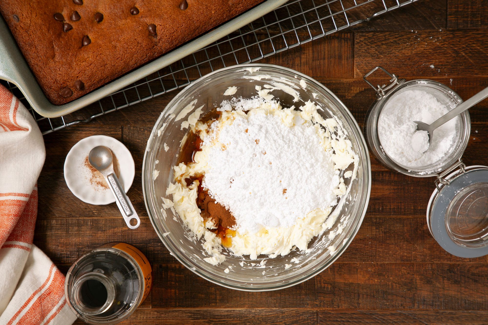 overhead shot of creamed cheese-butter, sugar, maple syrup, cinnamon and salt in a large glass bowl on wooden surface