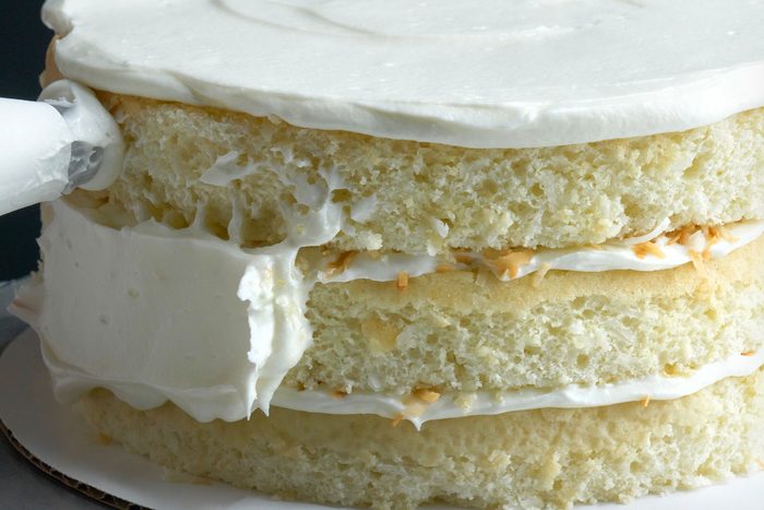 Close shot of spreading frosting over top and side of cake;