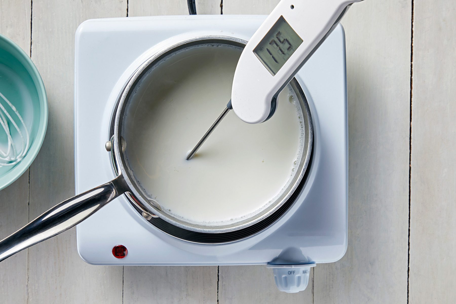 overhead shot; white background; In a small saucepan, heating the milk and checking the temperature with digital thremometer;