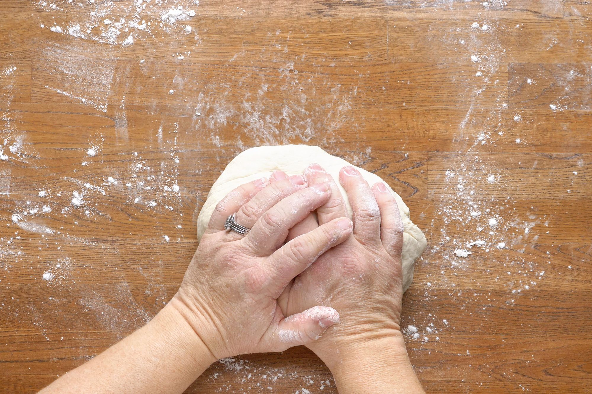 Dough kneaded by hands on a wooden surface