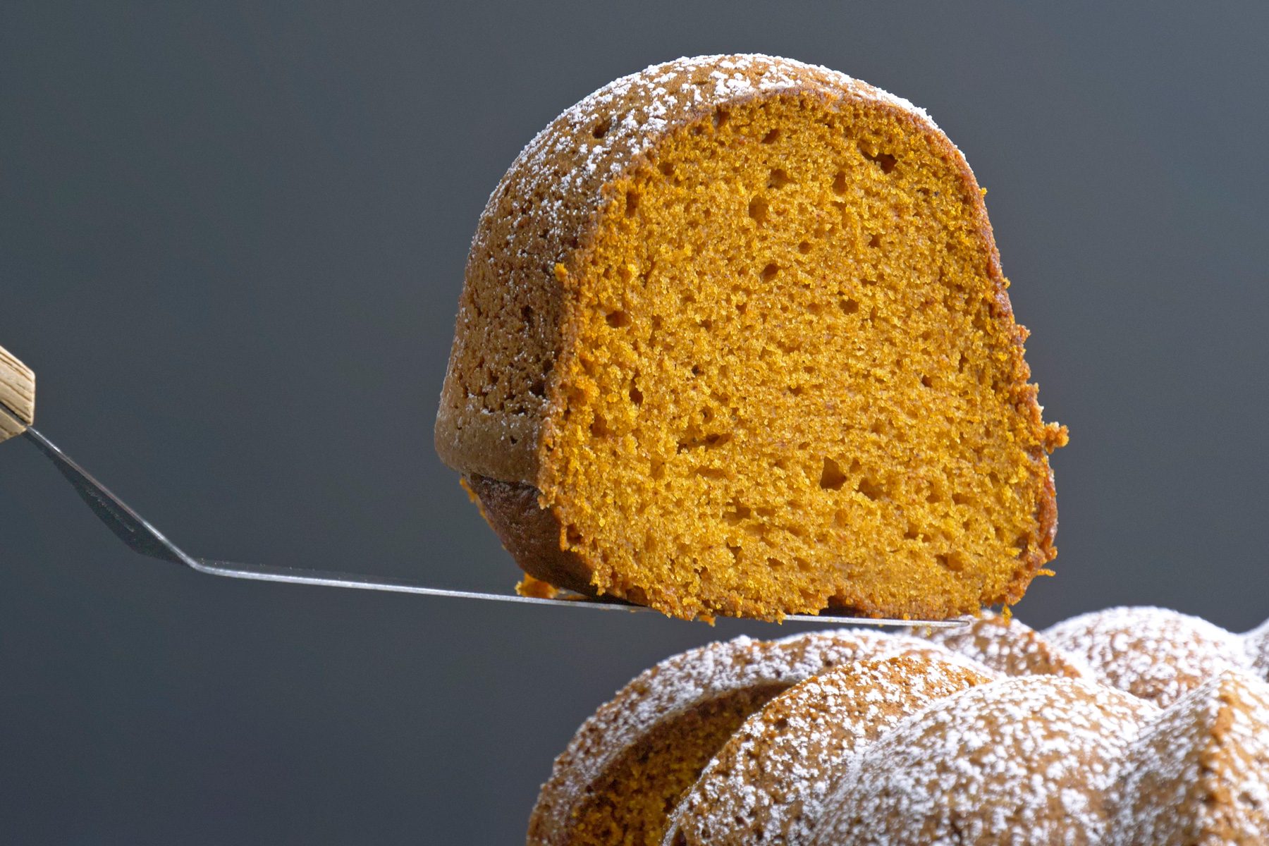 A person serving a piece of pumpkin bundt cake