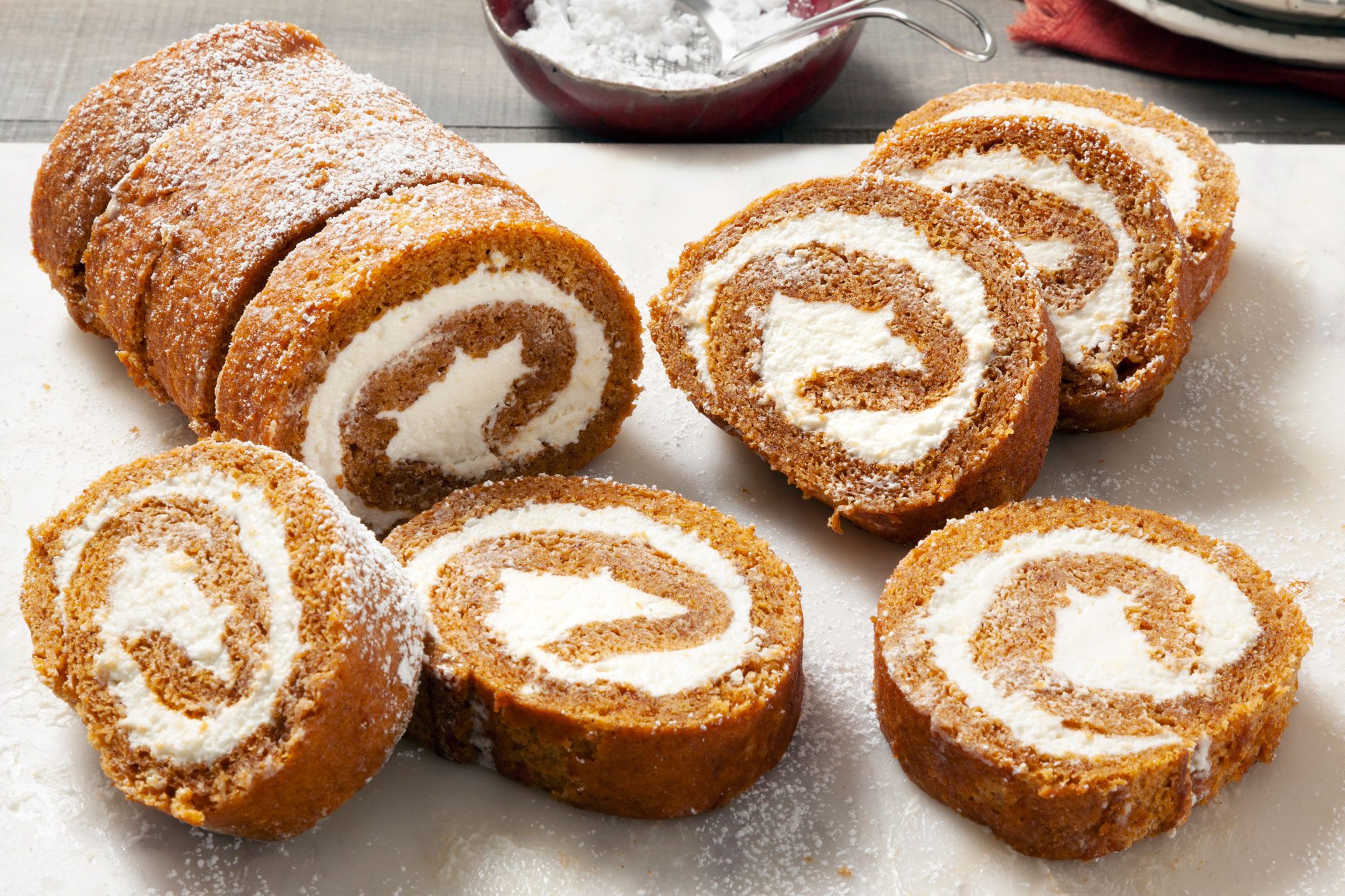 3/4 angle shot of Pumpkin Rolls; marble background; knife;