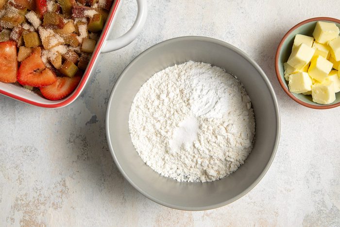overhead shot of flour, baking powder and salt in a white bowl with butter cubes