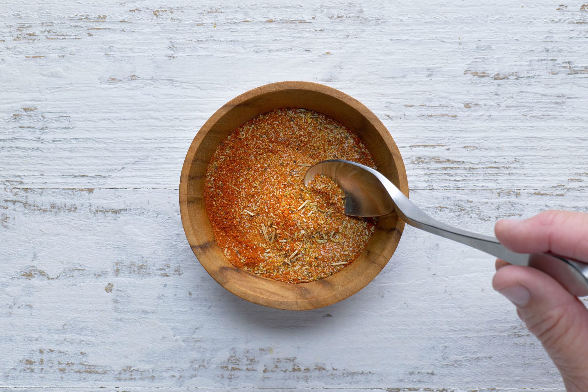 Overhead shot of mix seasonings in a small bowl; spoon; white wooden background;
