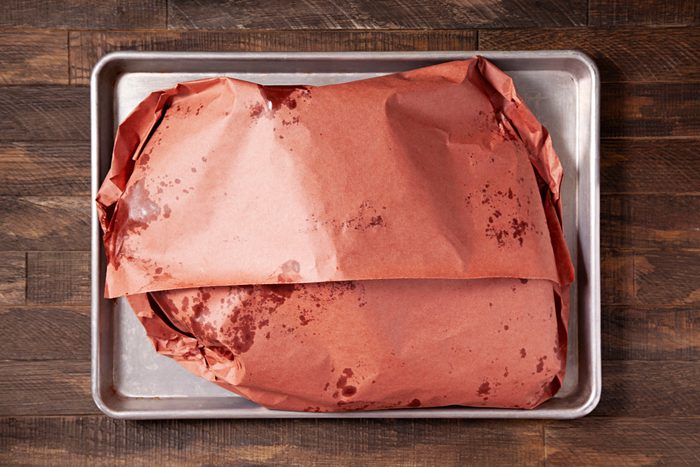 Wrapped beef in unwaxed paper placed in a tray.