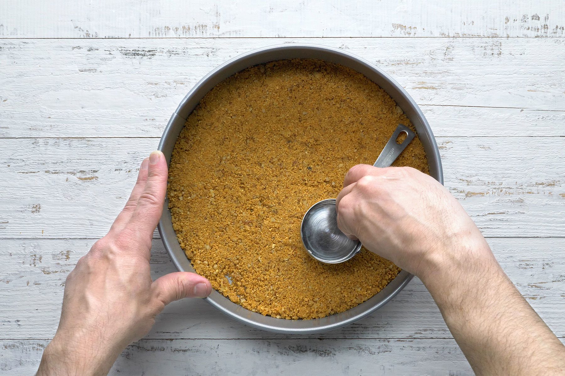 Overhead shot of combine pecans, crumbs and butter; press onto the bottom of a springform pan; wooden background;
