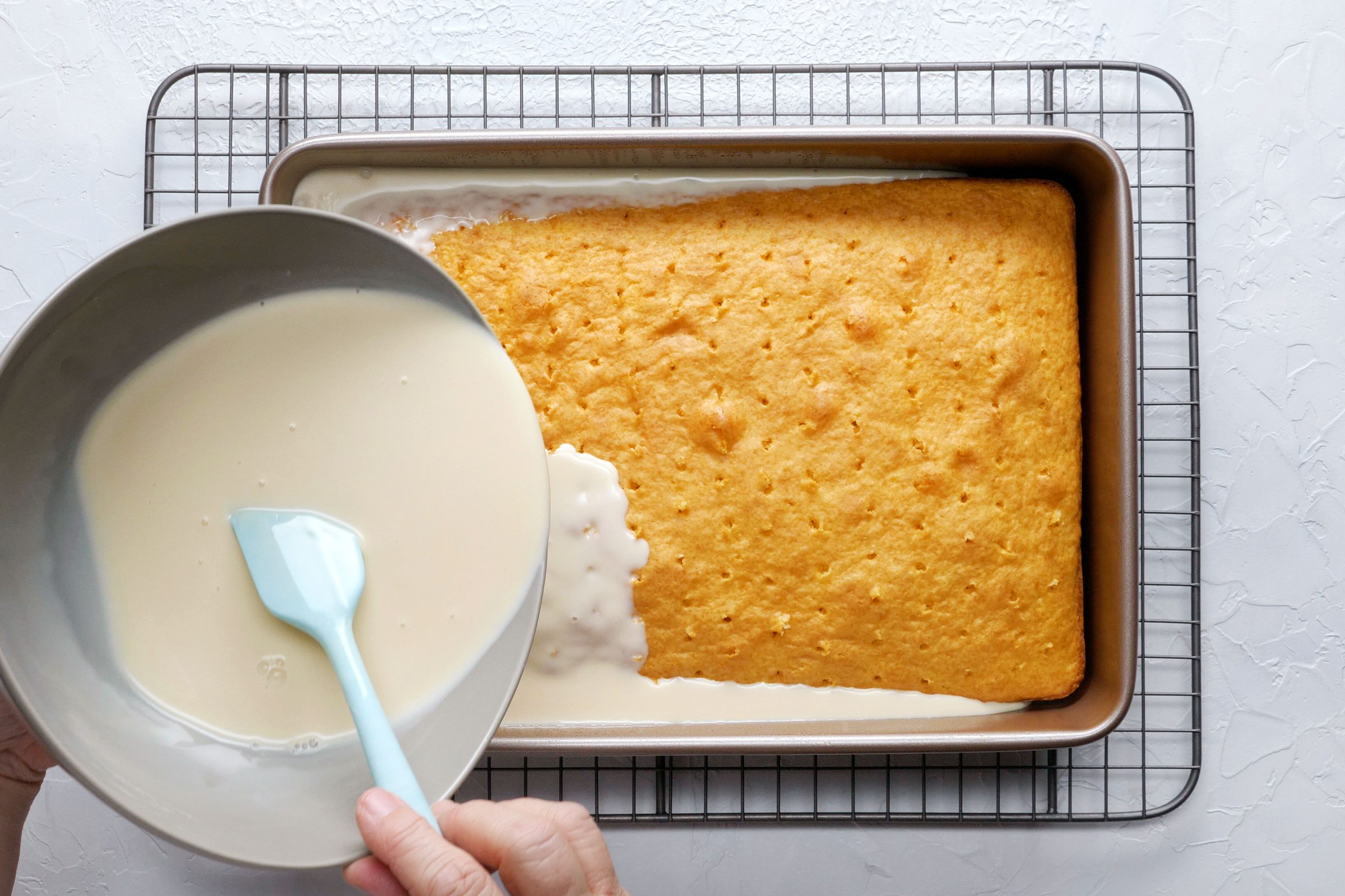 pouring milk onto tres leches cake