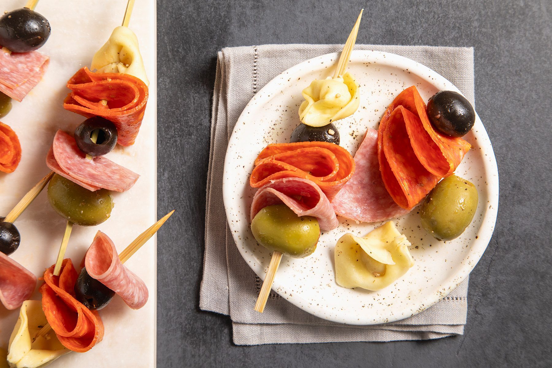 overhead shot; grey textured background; Antipasto Kabobs served in a small plate over kitchen towel