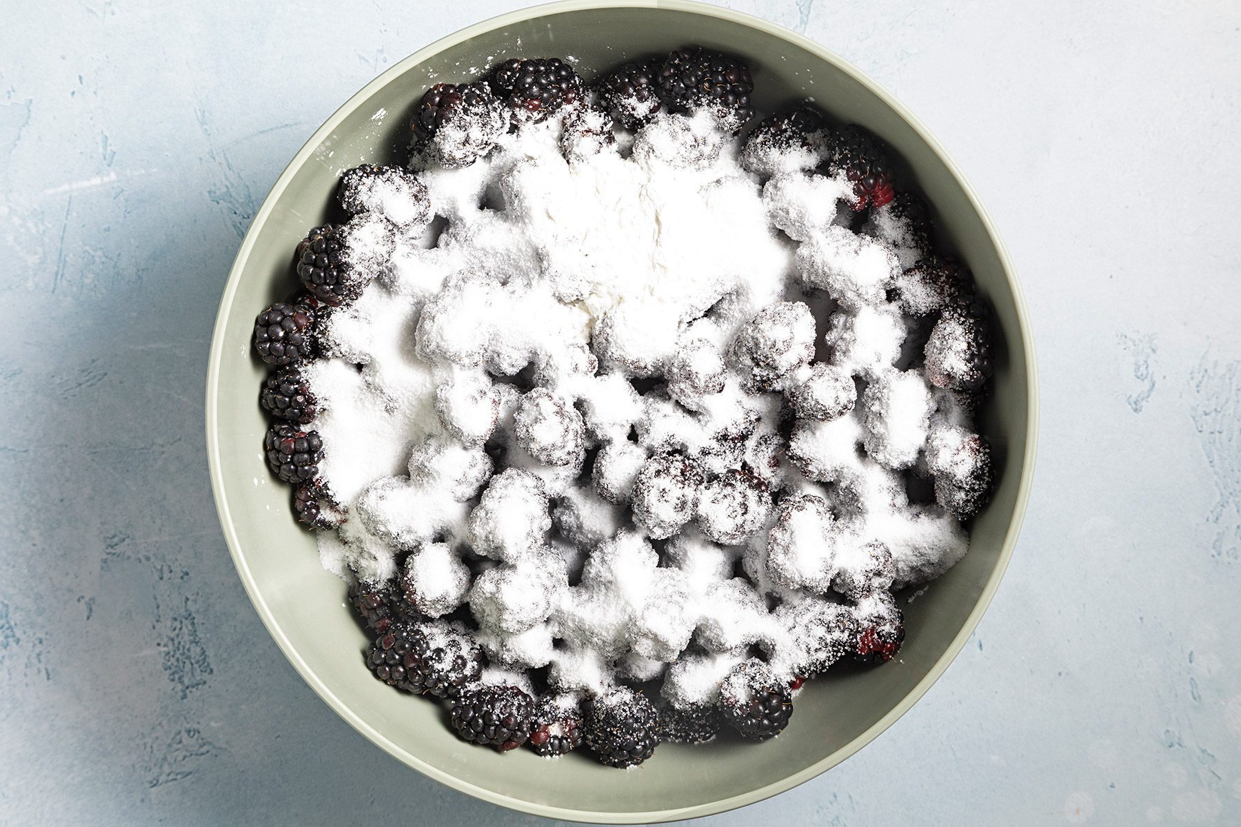 Overhead shot of same bowl; sprinkled with sugar and cornstarch; toss gently to coat; blue marble background
