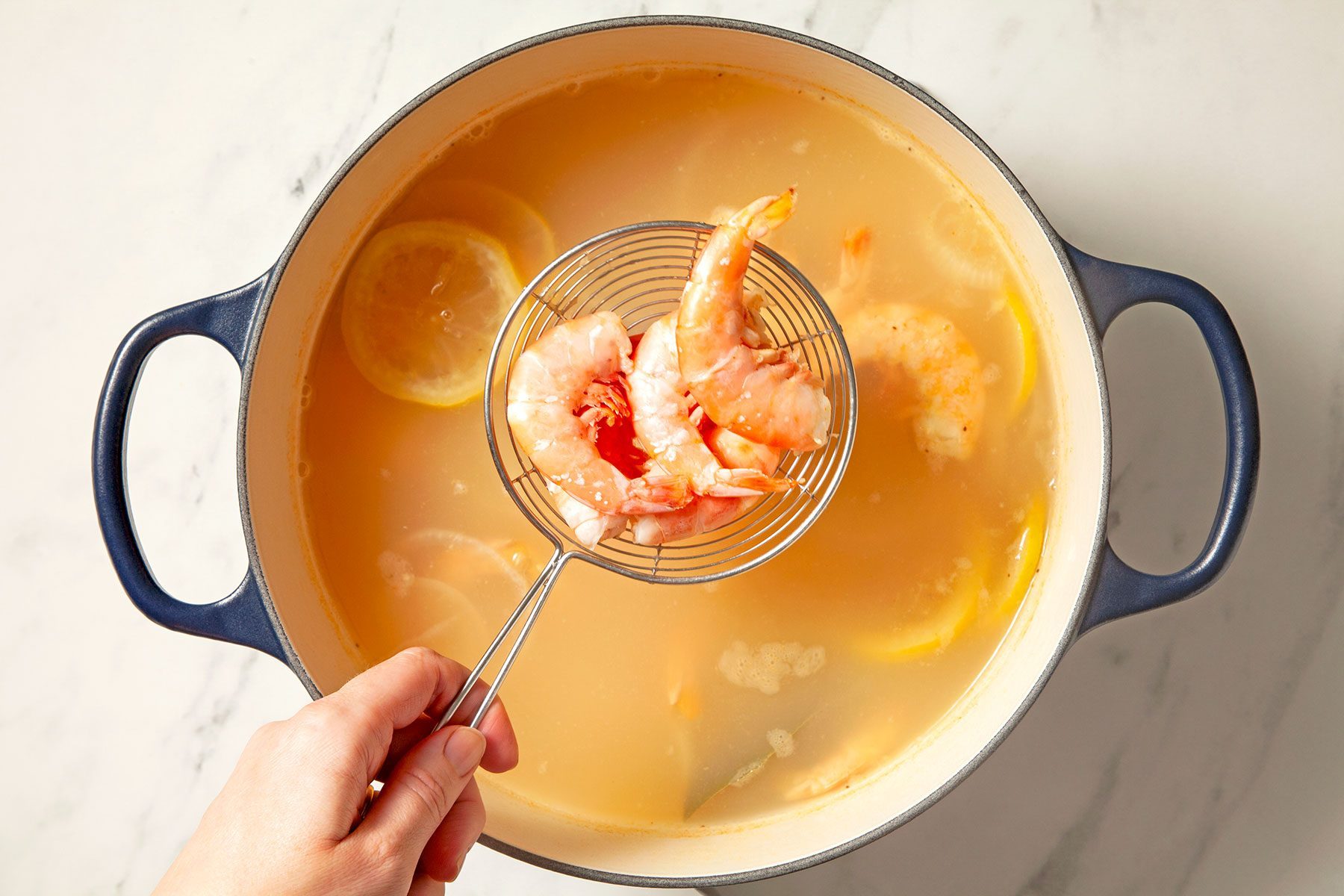 overhead shot of shrimps drained from saucepan