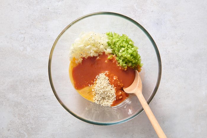 Combining bread crumbs, celery, onion, eggs, Buffalo sauce, garlic and pepper in a bowl
