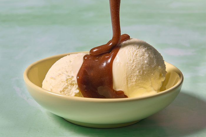 Closeup image of butterscotch sauce being poured over vanilla ice cream
